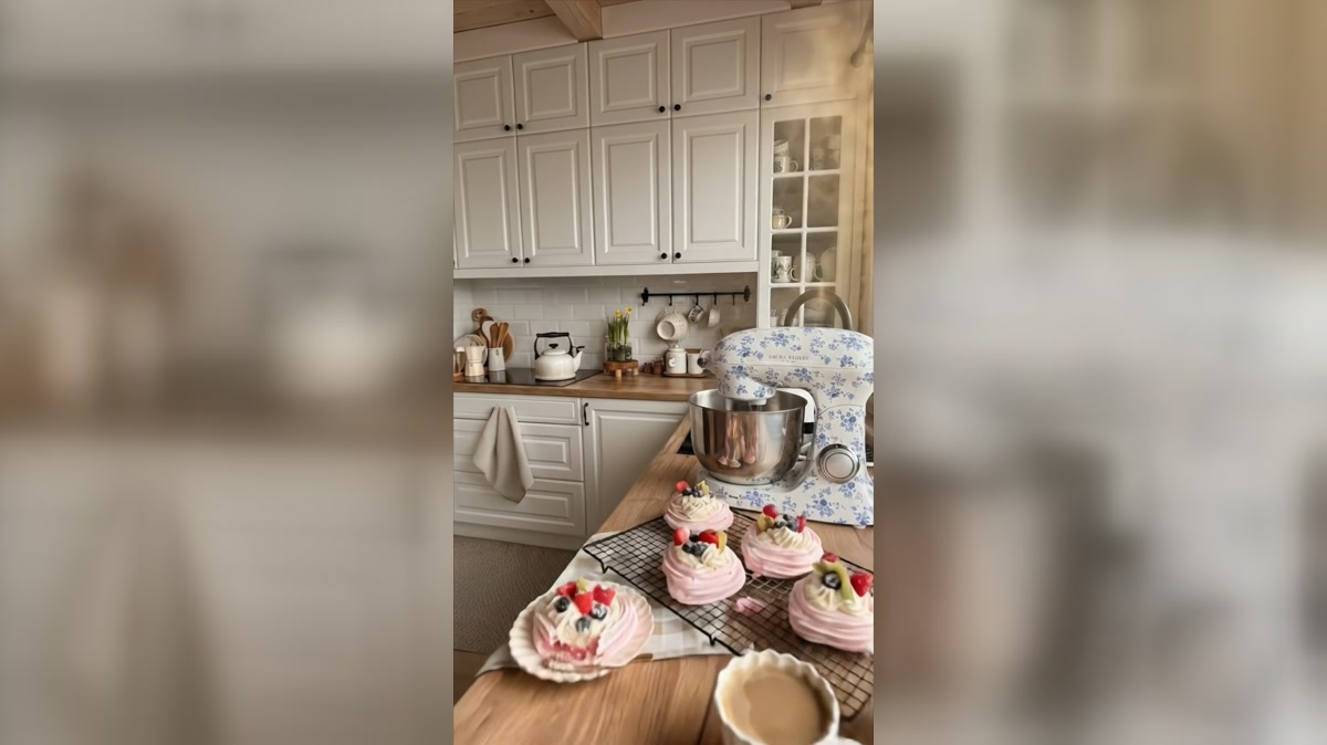 Baking station with mixer, small cakes, and warm timber worktop