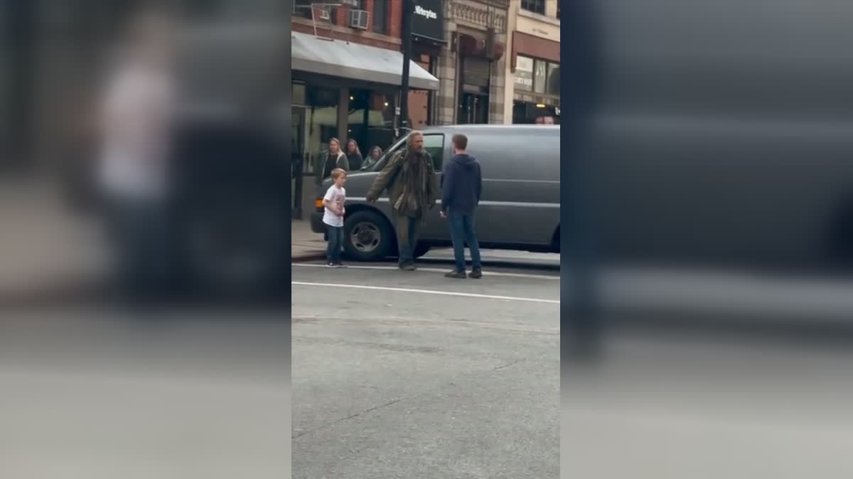 A man notices a child near the curb beside a parked van