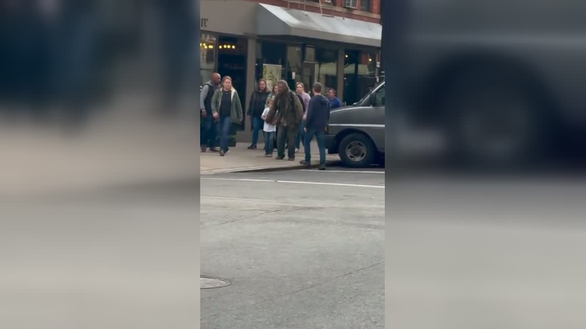 Bystanders gather after the tense street moment has passed