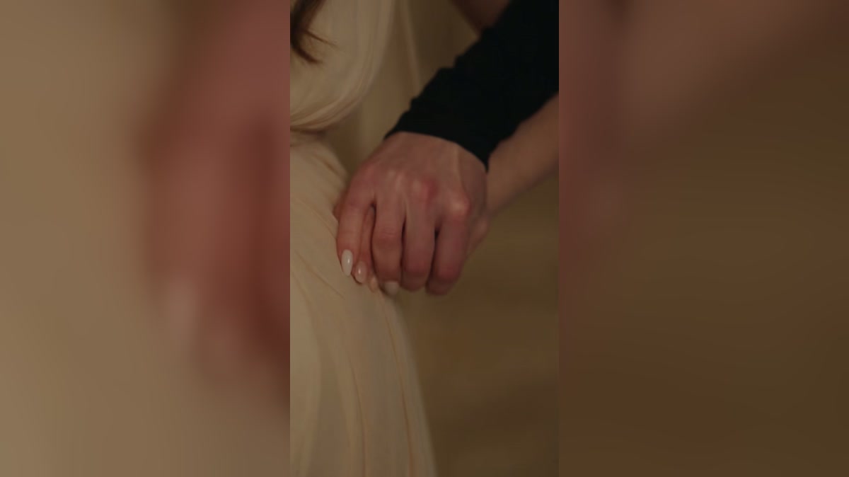 A dramatized scene in which a pregnant woman’s wrist is being held